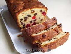 a loaf of fruit bread sitting on top of a white plate with slices cut off