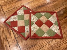 two red and green quilted placemats sitting on top of a wooden floor