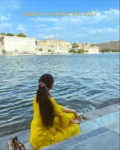 a woman sitting on the edge of a lake