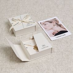 an open box with a necklace inside on a table next to a photo and other items