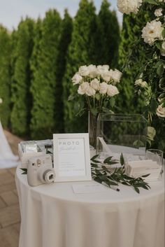 the table is set up with white flowers and greenery