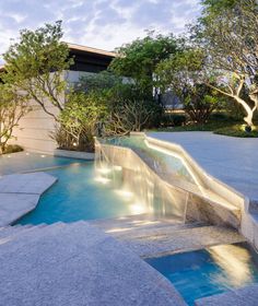 a water slide in the middle of a swimming pool with trees and bushes around it