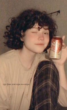 a woman with curly hair holding a can of beer