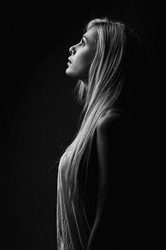 a black and white photo of a woman with long hair looking up at the sky