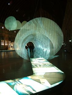 people are standing in an open space with large white balls hanging from it's ceiling