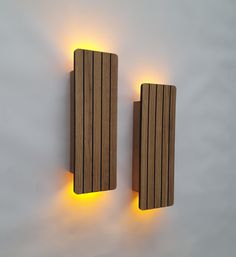 two wooden lights are on the wall next to each other, one light is yellow