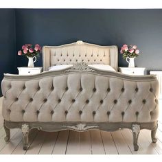 a white bed sitting on top of a wooden floor next to two vases filled with flowers