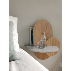 a bottle and glass on a shelf next to a bed with white linens in the background