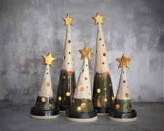 three small christmas trees with gold stars on them, sitting in front of a concrete wall