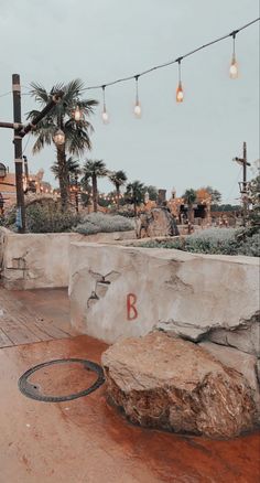 a stone bench sitting on top of a wooden floor next to palm trees and lights