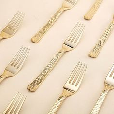 there are many forks and spoons lined up on the table together, all in different sizes