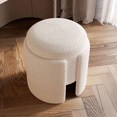 a white stool sitting on top of a hard wood floor next to a curtained window