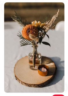 there is a vase with flowers in it on a wooden stand next to a candle