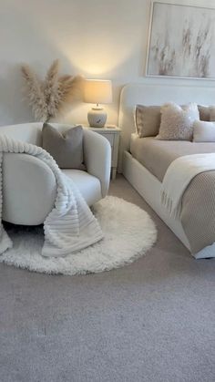 a white bed sitting next to a chair in a bedroom on top of a carpeted floor