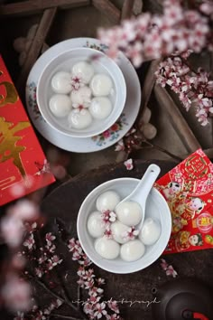 two bowls filled with white balls sitting on top of a table next to a red book