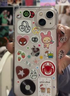 someone is holding up their phone case with many stickers on the back of it