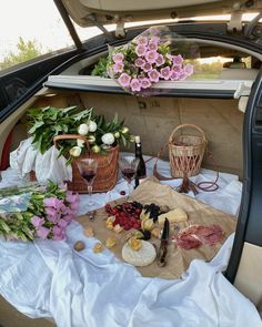 the trunk of a car with flowers and wine in baskets on it's back