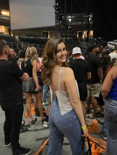 a woman standing in front of a group of people at a convention or show with orange tape on the ground