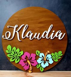 a wooden sign that says klaudia with flowers and leaves painted on the front