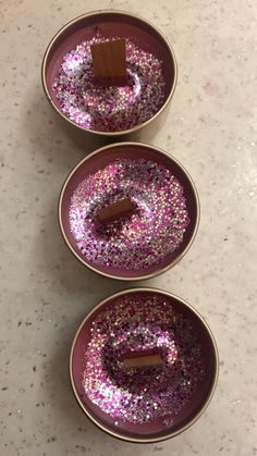 three purple plates with small pieces of chocolate in them sitting on a white counter top