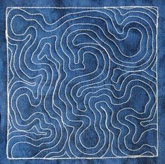 a blue piece of cloth with white stitching on it and a square shaped design in the middle