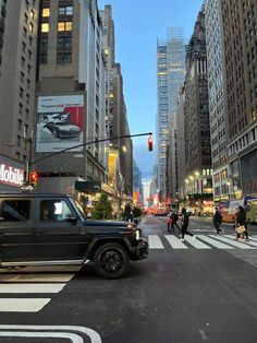 a black jeep driving down a street next to tall buildings in the city at night