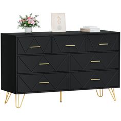 a black dresser with gold legs and a vase filled with flowers on top of it