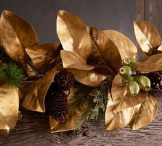 a wooden table topped with gold leaves and pine cones