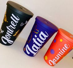 three different colored cups sitting next to each other on top of a white countertop