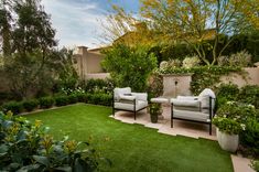 two white chairs sitting on top of a lush green field