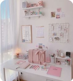 a white desk topped with lots of pink items and decor on it's walls