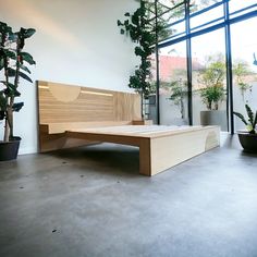 a bed sitting in the middle of a room next to potted plants and windows