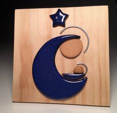 a wooden plaque with a blue moon and star on it's side, in the shape of a crescent