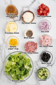 the ingredients to make this salad are shown on a marble counter top, including lettuce, tomatoes, cucumbers, black olives, parmesan cheese and red onion