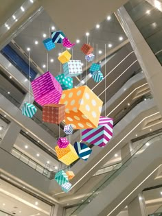 colorful paper cubes hanging from the ceiling in a large room with high ceilings and lights