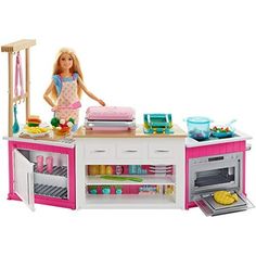 a barbie doll standing in front of a pink and white kitchen island with food on it