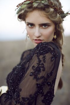 a woman with long hair wearing a black dress and a flower crown on her head