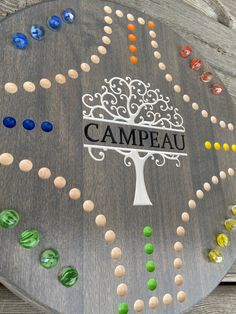 a wooden board with the word campau on it and a tree surrounded by multicolored beads