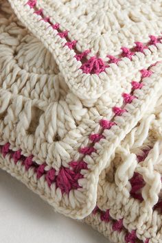 two crocheted blankets sitting on top of each other, one pink and the other white