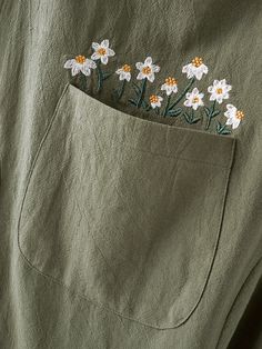 a green shirt with white daisies embroidered on it