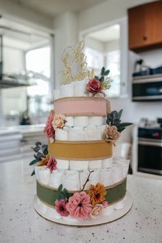 a multi - tiered cake with flowers and ribbons on the top is sitting on a kitchen counter