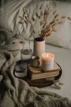 an arrangement of candles, books and other items on a bed with white linens