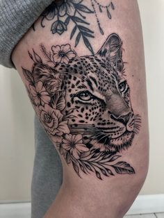 a woman's thigh with a tattoo of a leopard and flowers