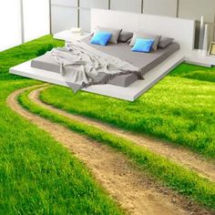 a bed sitting on top of a lush green field next to a dirt road in the grass