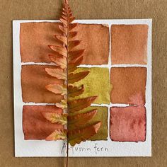 an orange and red leaf on top of a piece of paper that says autumn fern