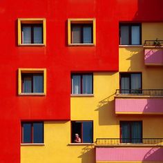 an apartment building with multiple balconies and windows painted red, yellow, pink, and blue