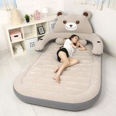 a woman laying on an inflatable bed with a teddy bear shaped pillow above it