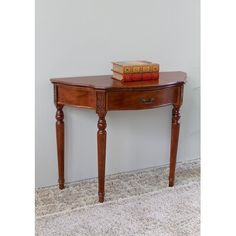 a small wooden table with two books on it's top and one drawer at the bottom