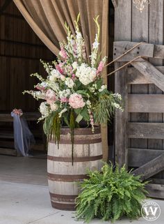 a wooden barrel with flowers and greenery in it