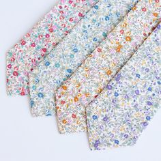 five different colored floral ties laid out on a white surface